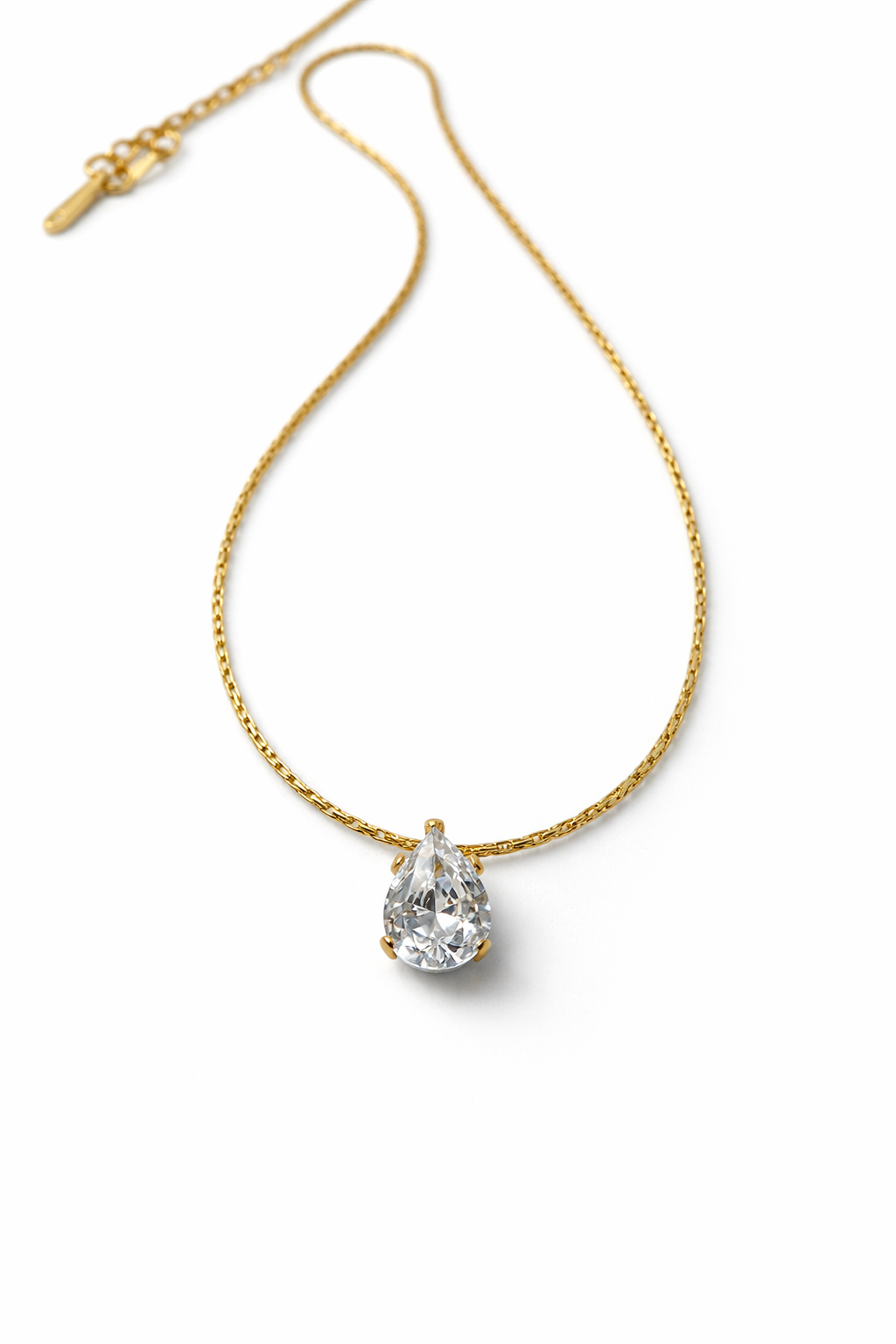 Gold necklace with a teardrop-shaped diamond pendant on a white background by Zenva
