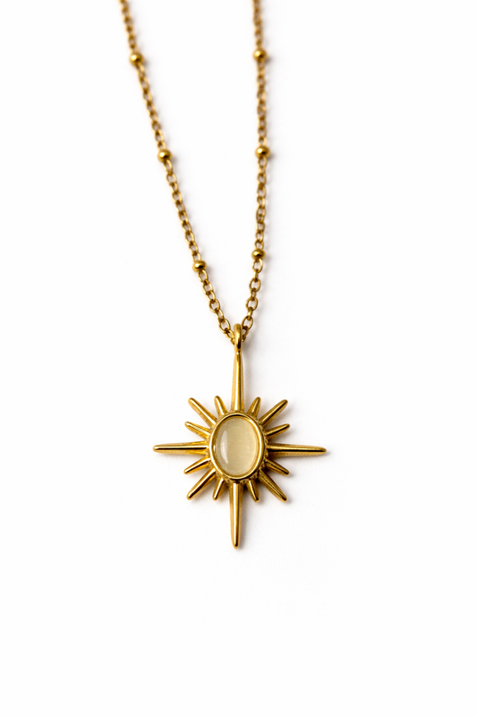 Gold necklace with a sun-shaped pendant on a white background by Zenva