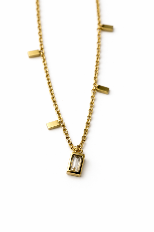 Gold necklace with rectangular pendant on a white background by Zenva